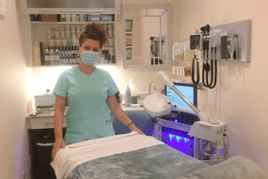 Esthetician standing in spa wearing a mask with products in the background