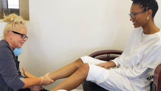 Manicure student receiving a pedicure demonstration from her instructor